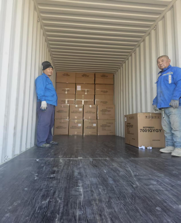 Workers loading boxed furniture into a shipping container